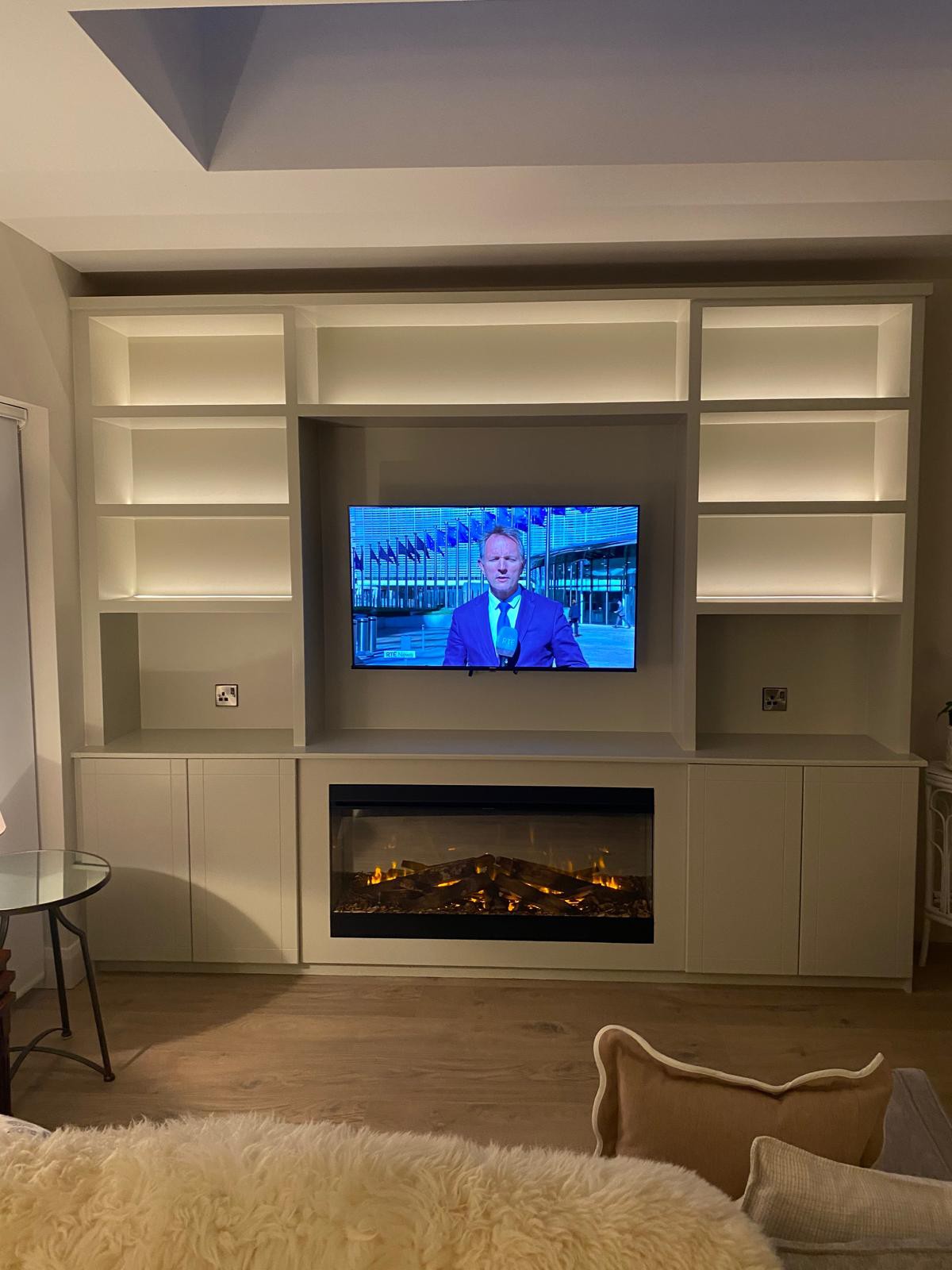 Bespoke built-in media wall with TV, alcove shelving and electric fireplace